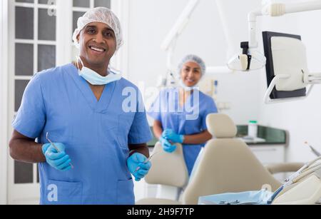 Lächelnder qualifizierter Stomatologe, der in der Zahnarztpraxis posiert Stockfoto