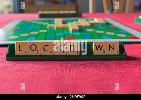 Scrabble-Token bilden einen Wortsperre auf dem Halter vor dem Spielbrett Stockfoto