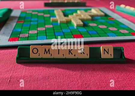 Scrabble-Token bilden das Wort omikron auf dem Halter vor dem Spielbrett Stockfoto