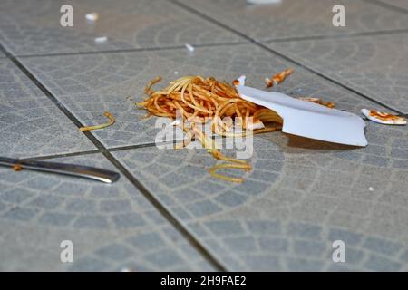 Abgefallener Teller mit Pasta auf dem Küchenboden Stockfoto