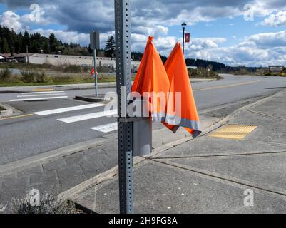 Woodinville, WA USA - ca. April 2021: Blick auf die Crosswalk-Flaggen in ihrem Halter neben einem Crosswalk in der Innenstadt Stockfoto