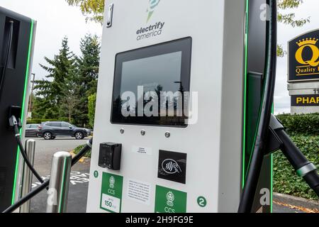 Kirkland, WA USA - ca. September 2021: Straßenansicht einer Elektroauto-Ladestation auf dem Parkplatz eines QFC-Lebensmittelladens. Stockfoto