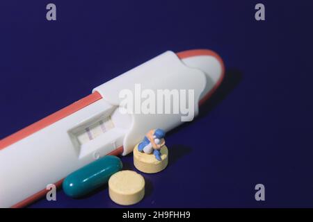 Konzeptfoto Mini Figur trauriger Mädchen und Schwangerschaft Testpaket positives Ergebnis Stockfoto