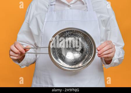 Koch mit Sieb in der Hand auf Studiohintergrund, Mockup-Kopierraum Stockfoto