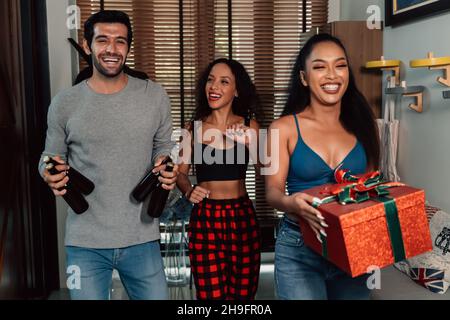 Gruppe von fröhlichen und lustigen männlichen und weiblichen Freunden mit Bierflaschen Geschenke zu Hause für eine schöne Hauswarmfeier während weihnachten ankommen Stockfoto