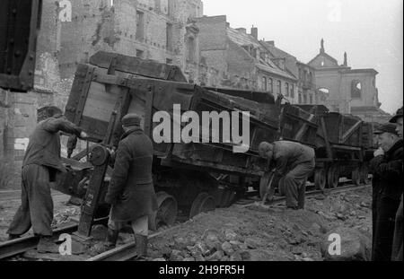 Warszawa, 1948-03. Odgruzowywanie Starego Miasta. NZ. Robotnicy pracuj¹cy przy wykolejonym wagoniku kolejki w¹skotorowej s³u¿¹cej do wywozu gruzu ze zburzonych kamienic. W g³êbi widoczne ruiny koœcio³a œw. Jacka Ojców Dominikanów przy ulicy Freta nr 10. uu PAP Dok³adny dzieñ wydarzenia nieustalony. Warschau, März 1948. Entfernung von Trümmern aus der Altstadt. Im Bild: Arbeiter mit einem entgleisten Schmalspurwagen, der Schutt aus bombardierten Gebäuden transportierte. Im Hintergrund Ruinen der Dominikanerpatres' St. Jack Church bei 10 Freta Street. uu PAP Stockfoto