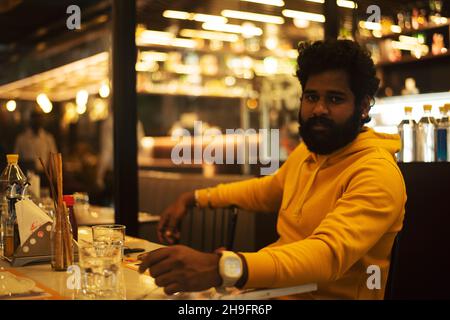 Gutaussehender Inder, der vor einem Restaurant wartet Stockfoto