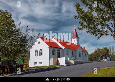 Schöne typische Kirche in Faskrudsfjordu oder Fáskrúðsfjörður auf Island. Weiße Wände und rotes Dach an einem sonnigen Tag in Island. Stockfoto