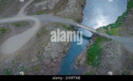 Brücke über den Fluss in island. Direkte Luftaufnahme einer Brücke über stilles Wasser. Stockfoto