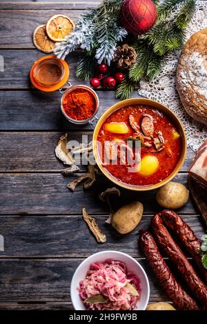 Top of view bei der Kohlsuppe - Kapustnica und Zutaten für die Zubereitung: Sauerkraut, Wurst, geräucherter Hals und Knie, Kartoffeln, Zwiebeln, getrockneter Moschus Stockfoto