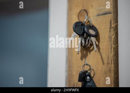 Die Autoschlüssel hängen an einem Holzhalter. Schlüsselübergabe bereit zur Entnahme. Stockfoto