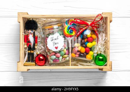 Handgemachtes Pflegepaket, saisonale Geschenkbox mit Süßigkeiten, Tasse auf weißem Tisch Personalisierter umweltfreundlicher Korb für Familie, Freunde, Mädchen für Danksagedanken Stockfoto