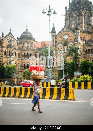 MUMBAI, INDIEN - 2. Oktober 2021 : nicht identifizierter Träger mit Covid-19 Maske, der einen Obstwagen an der CST-Station in Mumbai trägt Stockfoto