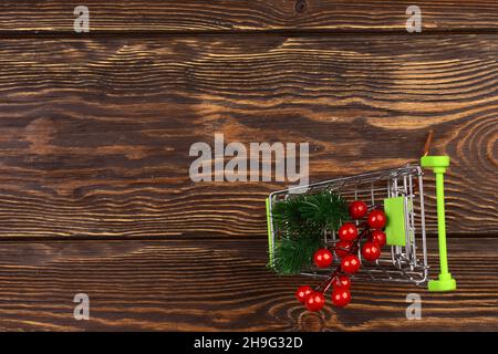 Warenkorb mit weihnachtseinkäufen auf Holzhintergrund. Minimalistischer, skandaliger Stil. Draufsicht, flacher Stil. Stockfoto