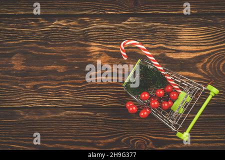 Warenkorb mit weihnachtseinkäufen auf Holzhintergrund. Minimalistischer, skandaliger Stil. Draufsicht, flacher Stil. Stockfoto