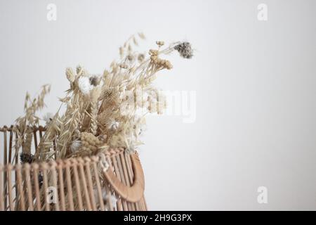 Getrockneter Blumenstrauß in Holzkorb auf weißem Hintergrund mit Kopierraum; Innenarchitektur; Konzept; schöner Hintergrund Stockfoto