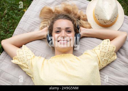 Junge Frau entspannt liegen und Musik hören Stockfoto