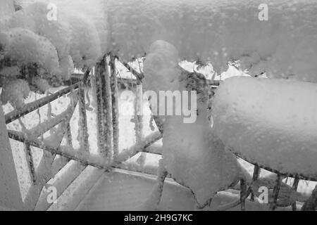 Abstrakt Winter verschneiten Hintergrund. Selektiver Fokus. Innen. Schneebedeckte Sommermöbel auf dem Balkon durch Eistropfen auf dem Glas auf dem Winter-Klo Stockfoto