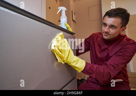 Professioneller Reiniger in Gummihandschuhen, der Schuhschrank entstaubt Stockfoto