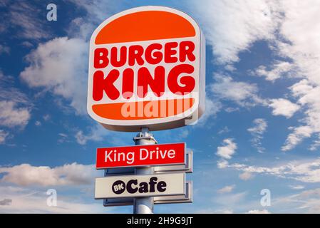 Monalieri, Turin, Italien - 6. Dezember 2021: schild mit neuem Logo des Burger King Restaurants mit King Drive am blauen Himmel mit Wolken in der Via Fortuna Stockfoto