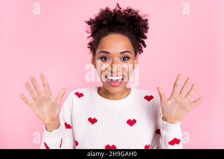 Foto von niedlichen lockigen Frisur Millennial Dame zeigen Waffen tragen weißen Pullover auf rosa Hintergrund isoliert Stockfoto