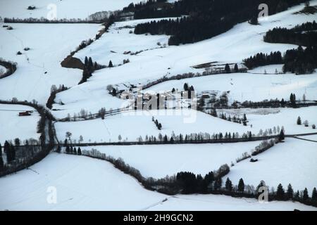 Luftaufnahme der schneebedeckten Alpen, Häuser und Bäume Stockfoto
