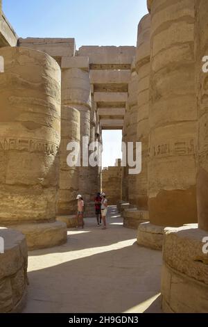 Menschen auf einem Ausflug in die zentrale Kolonnade des Karnak-Tempels. Touristen unter den antiken Ruinen. Berühmtes ägyptisches Wahrzeichen mit Hieroglyphen und Dekaye Stockfoto