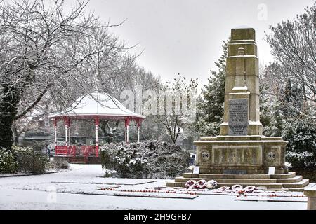 Winterschnee im Denton Victoria Park in Tameside mit seinem denkmalgeschützten edwardianischen Bandstand und dem WW1 war Memorial Stockfoto