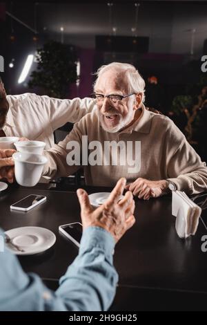 Ältere multikulturelle Freunde klirren Kaffeetassen, während sie Zeit im Café verbringen Stockfoto