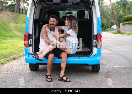 Das junge tätowierte Paar lächelte und umarmte sich hinten im Van. Stockfoto