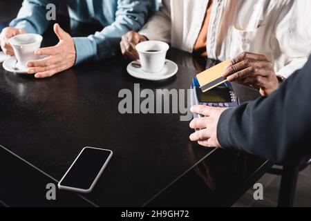 Kurzer Blick auf einen älteren Mann, der im Café mit Kreditkarte über das Terminal bezahlt Stockfoto