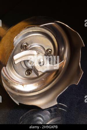 Stabmixer für die Zubereitung der Speisen auf schwarzem Hintergrund. Küchenausstattung aus Stählen. Instrument ruht mit Reflexion auf dem Tisch Stockfoto