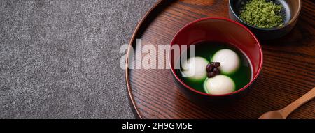 Nahaufnahme des großen Matcha tangyuan (tang Yuan) mit süßer Matcha-Suppe in einer Schüssel auf Holztischhintergrund für Festessen. Stockfoto