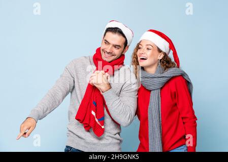 Portrait von glücklich lächelnd kaukasischen Paar in Weihnachten Outfits halten Hände in hellblau isoliert Studio Hintergrund Stockfoto