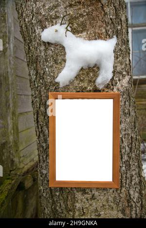 Kreativer Ansatz für Kinder. Die Kinder steckten eine Schneegarantie eines nördlichen Rentiers auf einen Baum (wie ein Hochrelief). Holzrahmen mit Buchstaben Stockfoto