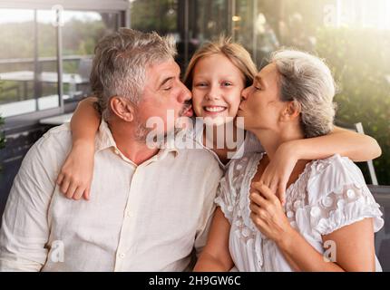Die Eltern küssen ihre Tochter. Der Mann und die Frau umarmen und küssen ihr Kind Stockfoto