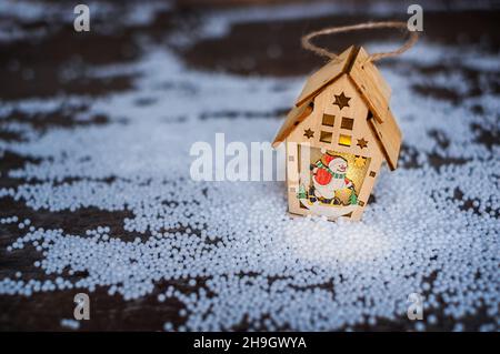 Laternenhaus mit brennender Kerze auf dem künstlichen Schnee am Abend. Feiern Sie Stockfoto