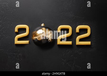 Frohes neues Jahr 2022 goldene Zahl mit Kugel verziert Luxus Metallic Potal isoliert auf schwarzem Nacht Hintergrund. Urlaubskonzept. Draufsicht, Kopierbereich.
