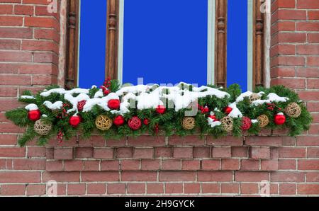 Fenster in einer Ziegelwand mit einer Weihnachtsdekoration. Mockup zum Einfügen eines Bildes oder Textes. Stockfoto