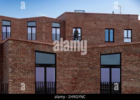 Fensterputzer bei der Arbeit (Abseiler, neues Hochhaus für Apartments und Wohnungen, Sicherheit) - Hudson Quarter, York City Centre, North Yorkshire, England Großbritannien. Stockfoto