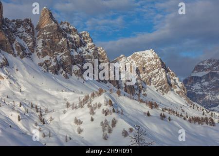 Schneebedeckte Pisten mit Lärchen am Fuße der imposanten Dolomitenwände Stockfoto