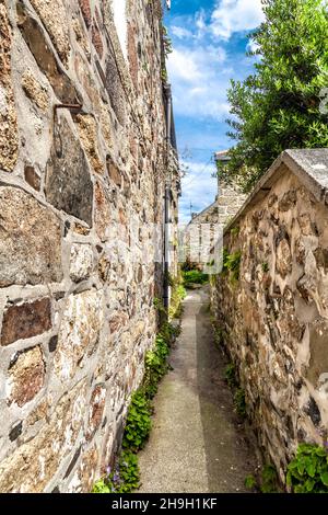 Schmale Passage zwischen Steinhütten im Fischerdorf Mousehole, Penwith Peninsula, Cornwall, Großbritannien Stockfoto