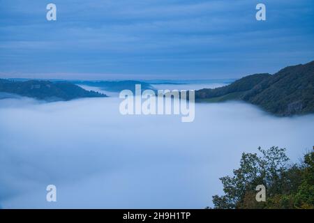 Nebel steigt auf den Bergen der kleinen Saarschleife. Mystische Stille an der Saar im Saarland. Stockfoto