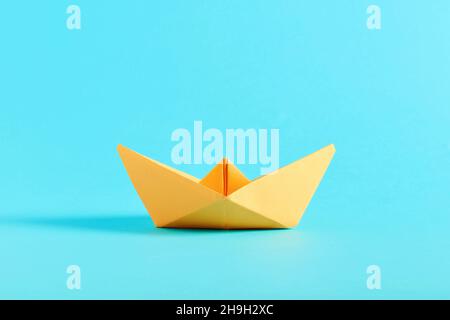 Origami gelbes Papierboot auf blauem Hintergrund. Stockfoto