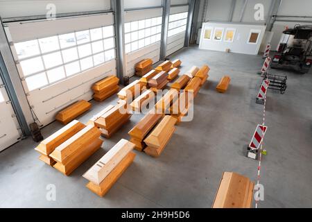 Dresden, Deutschland. 07th Dez 2021. Zahlreiche Särge liegen in einer Lagerhalle auf dem Gelände des Büros für Straßen- und Bauingenieurwesen Dresden. In der Halle, die normalerweise für Hochwasserschutzanlagen genutzt wird, können bis zu 400 Särge gelagert werden. Es soll die Logistik des Bestattungsdienstes vereinfachen, indem es vor der Verbrennung als Zwischenlager dient. Quelle: Sebastian Kahnert/dpa-Zentralbild/dpa/Alamy Live News Stockfoto