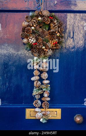 weihnachtskranz auf einer blau bemalten Haustür, festliche Hausdekorationen, Zeit Holztür blau mit hängenden weihnachtsdekoration gemalt, Weihnachten. Stockfoto