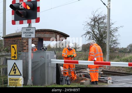 Frating, Großbritannien. 07. Dez 2021. Die Ingenieure überprüfen den Bahnübergang in Frating bei Colchester in Essex, nachdem ein Auto von einem vorbeifahrenden Zug abgeschnitten wurde. Kredit: Eastern Views/Alamy Live Nachrichten Stockfoto