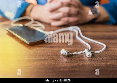 Handy oder Smartphone, Kopfhörer und Sonnenbrille die modernen Attribute der lässigen Männer liegen auf dem Tisch. Stockfoto