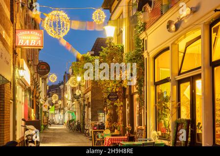 Alkmaar, Niederlande - 10. November 2021: Bunte Einkaufsstraße mit weihnachtlicher Dekoration im alten Stadtzentrum von Alkmaar, Niederlande Stockfoto