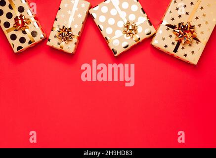 Geschenkboxen mit goldenen Schleifen und Bändern auf rotem Hintergrund. Stockfoto